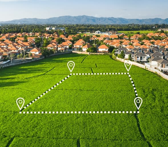 An open green parcel of land outlined with map markers beside a residential neighborhood