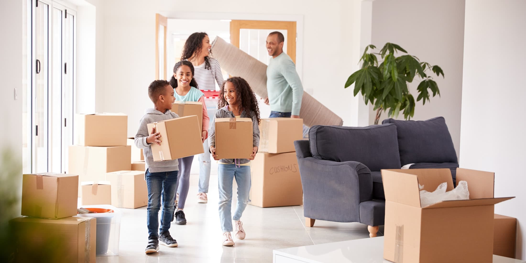 A family carrying moving boxes into their new home
