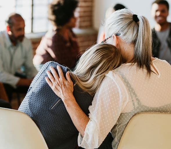 Two women embracing during a supportive group conversation